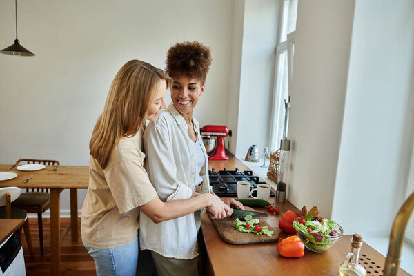 Couple shares laughter while preparing a fresh salad in their stylish kitchen.