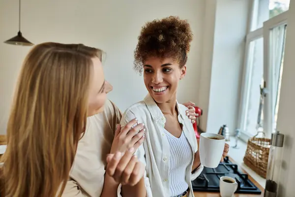 stock image Two smiling partners enjoy each other's company over coffee in a warm, inviting kitchen.