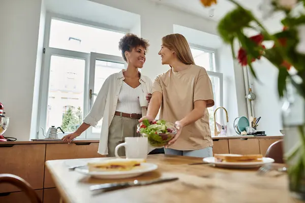 stock image Couple shares a light moment while preparing a fresh salad in their bright kitchen.