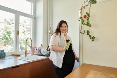 Kendinden emin, iri yarı bir kadın evde eğlenirken gülümsüyor..