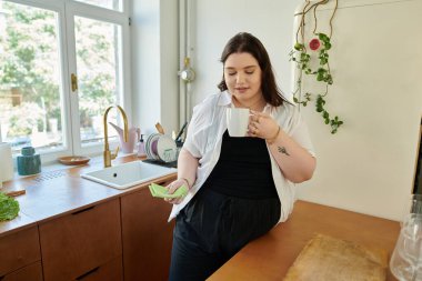 Ayrıca boyunda bir kadın şık mutfağında sıcak bir fincan çayın tadını çıkarıyor..