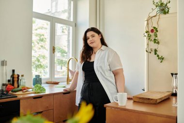 Kendine güvenen bir kadın evinde dinleniyor, huzurlu mutfak sabahının tadını çıkarıyor..