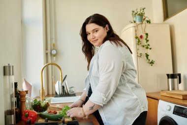 A vibrant woman joyfully prepares fresh vegetables in her inviting kitchen. clipart