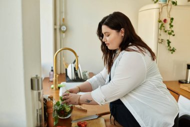 Büyük beden bir kadın mutfak tezgahında taze sebzeler hazırlar. Mutfak yaratıcılığını benimser..