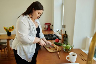 Güzel, iri yarı bir kadın, sıcak ve davetkar bir mutfakta ustaca sebze doğruyor..