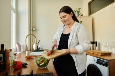 Büyük beden bir kadın sıcak mutfağında canlı bir salata hazırlar..