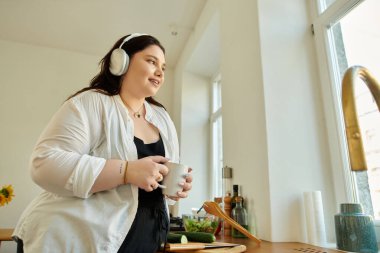 Mutlu kadın evde müzik dinlerken çayının tadını çıkarıyor..