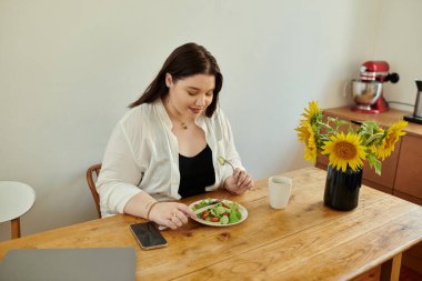 Bir kadın sıcak mutfak masasında besleyici bir yemeğin tadını çıkarır..