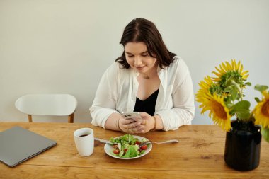 Bir kadın telefonunu kontrol ederken salata ve kahveden hoşlanır..