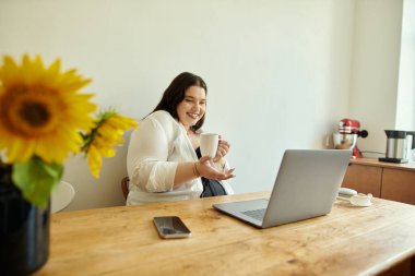 Neşeli bir kadın işiyle meşgulken kahvenin tadını çıkarır..