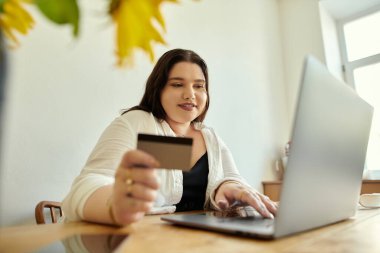 Bir kadın yemek masasında otururken internetten alışveriş yapıyor..