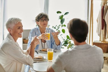 Neşeli bir aile kahvaltıdan keyif alır, kahkahaları ve sohbetleri krep ve meyve suyu eşliğinde paylaşır..