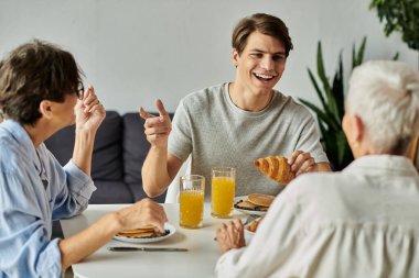 Lezbiyen ebeveynler ve yetişkin oğullarıyla neşeli bir kahvaltı, kahkahalar ve lezzetli yemekler..