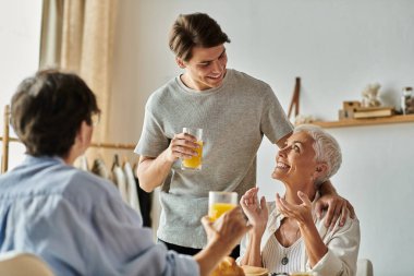 Sevgi dolu lezbiyen ebeveynler ve yetişkin oğulları arasında paylaşılan keyifli bir kahvaltı anı..