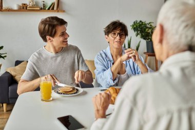 İki anne ve oğullarının gülümsemelerini ve lezzetli yemeklerini paylaştığı keyifli bir kahvaltı..
