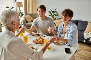 Neşeli bir kahvaltı. Lezbiyen ebeveynler ve yetişkin oğulları sevgi ve kahkaha paylaşıyorlar..