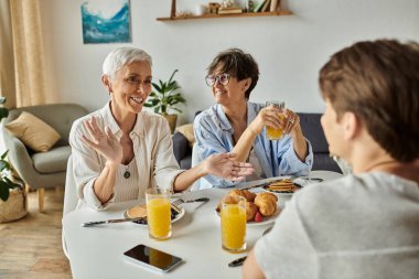 Lezbiyen ebeveynler sıcak ve davetkar bir atmosferde kahvaltılarını yetişkin oğullarıyla paylaşırlar..