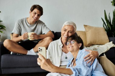 Üç aile ferdi birlikte eğlenceli bir anı yakalarken kahkaha ve neşeyi paylaşıyor..