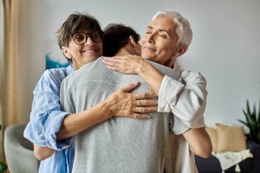 A loving lesbian couple and their adult son share a warm embrace, celebrating their strong family bond. clipart