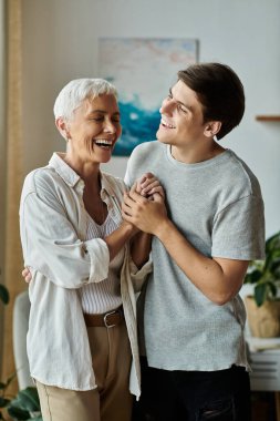 Orta yaşlı bir anne ve yetişkin oğlu sıcak bir yuva ortamında kahkaha ve sevgiyi paylaşıyor..