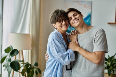 Bir anne ve oğlu sıcak bir şekilde kucaklaşır, kahkahalarını ve sevgilerini sıcak oturma odalarında paylaşırlar..