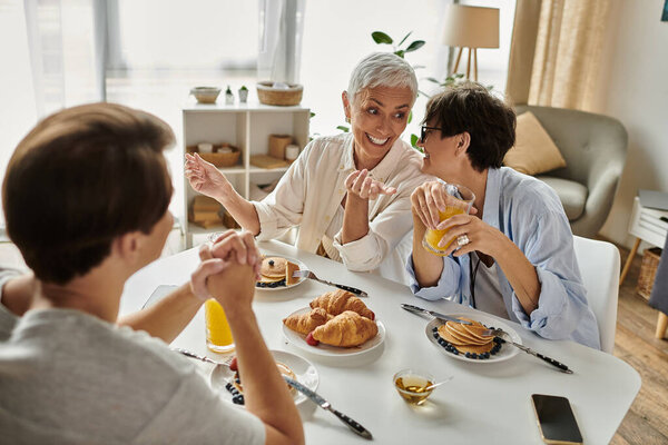 A loving LGBTQ family enjoys a cheerful breakfast together, sharing laughter and delicious food.