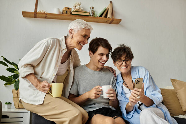 Любящая семья ЛГБТК наслаждается смехом и общением за чашечкой кофе, делясь моментами и улыбаясь вместе.