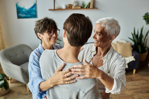 Радостная семья ЛГБТК обнимается в теплый момент общения и любви в своем приглашающем доме.