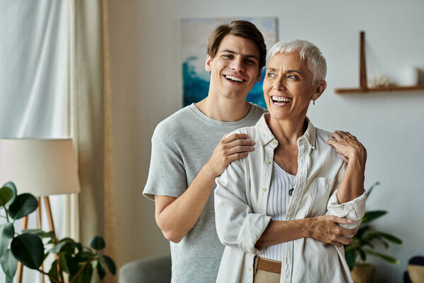 Мать и ее взрослый сын смеются и обнимаются, наслаждаясь драгоценными моментами в их яркой гостиной.