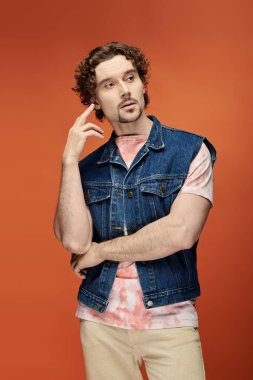 Düşünceli bir adam, parlak bir arkaplanda kendine güvenen bir ifadeyle poz verir..