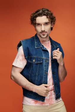 Şık bir adam, cesur ve renkli bir arkaplan önünde duygularını ifade eder..