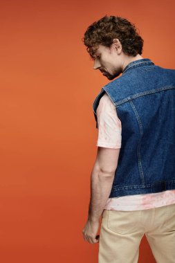 Yakışıklı bir adam, parlak turuncu bir arkaplanda poz verirken duygularını ifade eder..