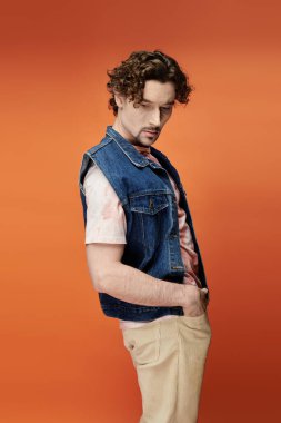 Zarif bir adam cesur turuncu bir arkaplan önünde duygularını sergiler..