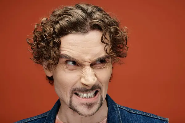 stock image A man displays intense emotion while posing on a bright backdrop.