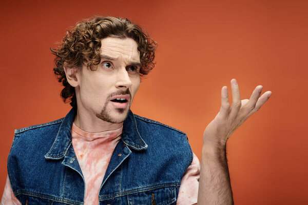 Красивый мужчина позирует эмоционально выразительным жестом.