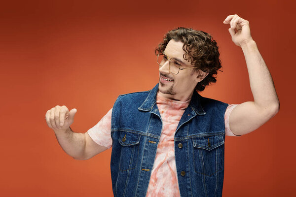 Стильный человек выражает радость игривым танцем на ярком фоне.