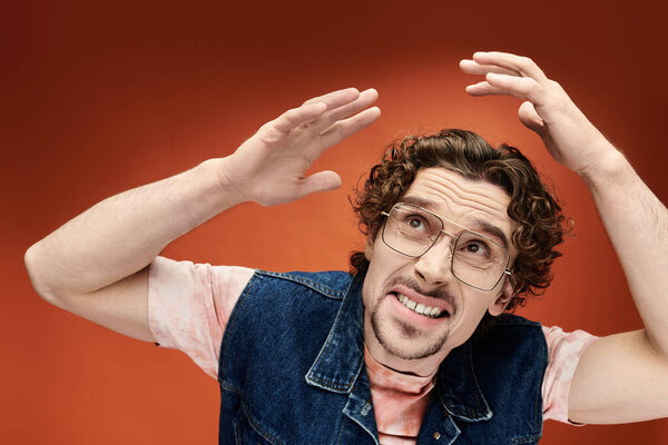 Красивый мужчина в очках показывает глубокие эмоции перед красочным фоном.