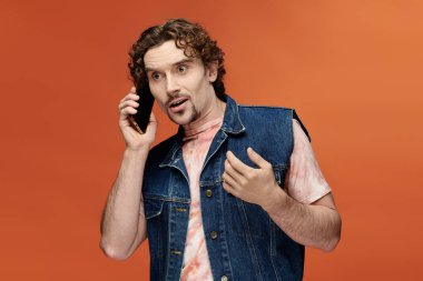 Handsome man passionately talking on the phone in a colorful environment. clipart