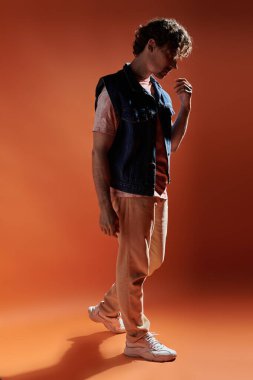 Şık bir adam düşünceli bir şekilde poz verir sıcak, renkli bir arkaplanda.