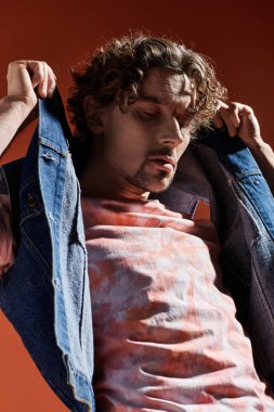 Yakışıklı bir adam duygusal yüz ifadesini canlı bir arka planla sergiliyor..