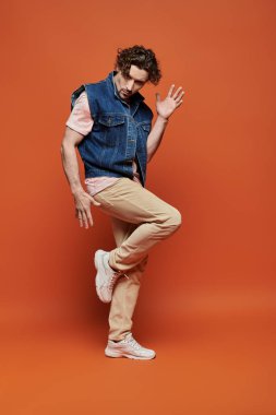 Duygusal adam poz verir, canlı bir arkaplan karşısında gösteriş yapar..