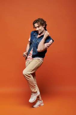 Bir adam sevinçle renkli bir arkaplanda çekici bir ifadeyle poz verir..