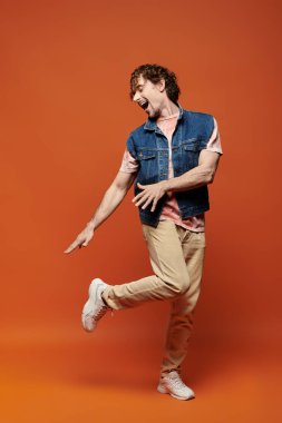 Canlı bir adam duygularını renkli bir arka planda neşeli bir pozla gösterir..