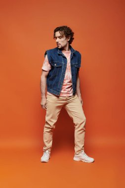 Yakışıklı bir adam canlı turuncu bir arka planda güvenle durur..