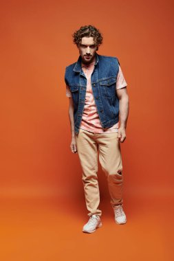 Çarpıcı bir adam canlı bir arka plana karşı duruyor, derin duygular ifade ediyor..