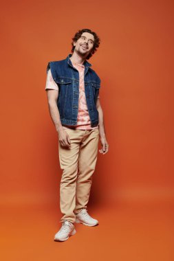 Tarz sahibi bir adam ışıl ışıl gülümser, renkli bir arkaplanda neşe dolu bir anın tadını çıkarır..