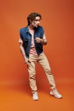 Yakışıklı bir adam cesur bir arkaplanda şık bir şekilde dururken duygularını ifade eder..