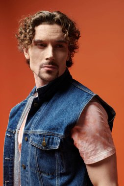 Yakışıklı bir adam, canlı bir arkaplanda poz verirken derin duygular sergiler..