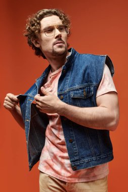 Duygusal adam canlı turuncu bir arkaplana karşı özgüvenle poz verir..