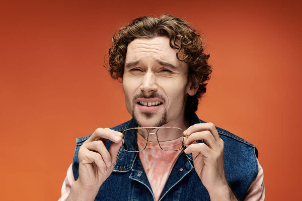 Красивый мужчина держит очки, отражая глубокие эмоции и созерцание.